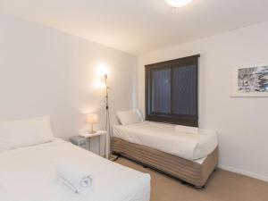 a bedroom with two beds and a window at Edge 6 16 Clyde Street in Jindabyne