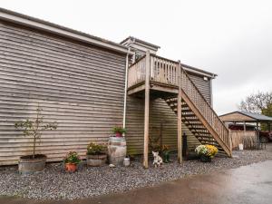 a deck on the side of a house with potted plants at The Cider Shed in Winscombe