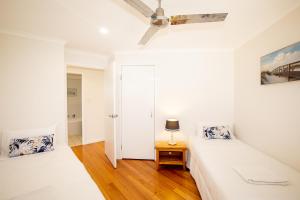 Dormitorio blanco con cama y mesa en BEST OCEAN VIEWS ON STRADDIE + SUNSET DECK en Point Lookout