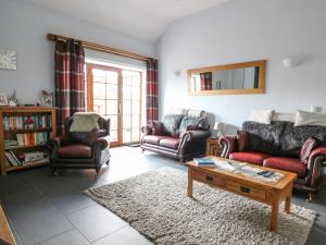 a living room with couches and a coffee table at Yr Hen Llaethdy in Troedyraur