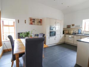 a kitchen with a wooden table and a kitchen with white cabinets at Yr Hen Llaethdy in Troedyraur