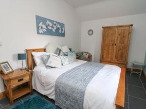 a bedroom with a bed and a wooden cabinet at Yr Hen Llaethdy in Troedyraur