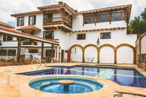 a villa with a swimming pool in front of a house at Casa de Campo Hotel & Spa in Villa de Leyva