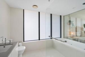 a bathroom with a tub and a toilet and windows at Circle on Cavill 2, 3, 4 & 5 Bedroom SkyHomes & SUB PENTHOUSES by Gold Coast Holidays in Gold Coast