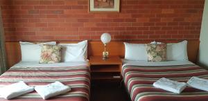two beds in a room with a red brick wall at All Rivers Accommodation in Echuca