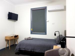 ein Zimmer mit einem Bett, einem Fenster und einem Schreibtisch in der Unterkunft Criterion Hotel Grenfell in Grenfell