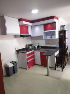 una cocina con armarios rojos y blancos y una mesa en Hermoso apartamento en Pasto. Central parque San Andrés, en Pasto