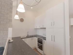 a white kitchen with white cabinets and a sink at Tanderra 17 28 Park Road in Jindabyne