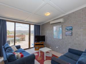 a living room with two blue couches and a tv at Tanderra 17 28 Park Road in Jindabyne