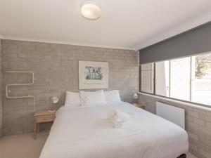 a bedroom with a white bed with a towel on it at Tanderra 17 28 Park Road in Jindabyne