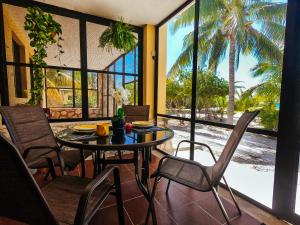 ein Esszimmer mit einem Tisch, Stühlen und einer Palme in der Unterkunft PRECIOSA VILLA FRENTE AL MAR in Celestún