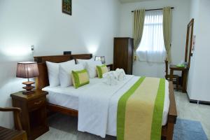 L S Lanka Boutique Hotel في دامبولا: غرفة نوم بسرير وبطانية خضراء وصفراء