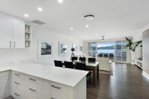una cucina e un soggiorno con tavolo e sedie di Frangipani Beachfront Lodge 202 on Hamilton Island by HamoRent a Hamilton Island