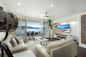 un soggiorno con un divano e una TV di Frangipani Beachfront Lodge 202 on Hamilton Island by HamoRent a Hamilton Island