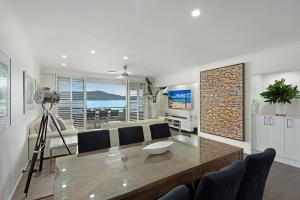 un soggiorno con un tavolo e un divano di Frangipani Beachfront Lodge 202 on Hamilton Island by HamoRent a Hamilton Island Altre 14 foto