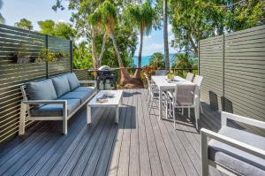 a deck with a couch and a table and chairs at Sunset Waters 12 on Hamilton Island by HamoRent in Hamilton Island
