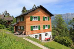 ein Haus auf einem Hügel mit grünen Rollläden in der Unterkunft Chalet Good in Flumserberg