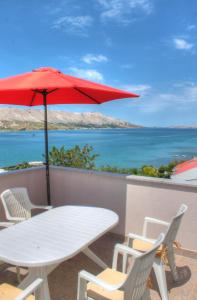 a white table and chairs with a red umbrella at Petros Apartments Pag in Pag
