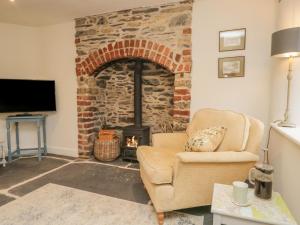 - un salon avec une cheminée en briques et une chaise dans l'établissement 1 Sunny Point Cottages, à Kendal