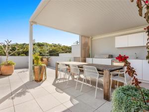 an outdoor patio with a wooden table and chairs at Driftwood Two at Clarkes Beach in Byron Bay