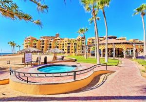 a resort with a swimming pool and palm trees at Right on the Beach! Ocean Front 2 Story Penthouse in Puerto Peñasco