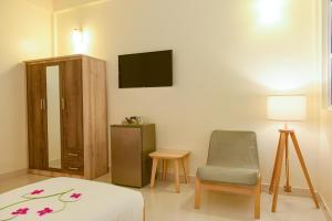 a room with a bed and a chair and a television at One The Island in Naifaru