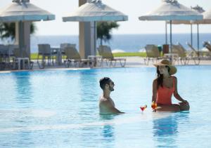 a woman and a man sitting on surfboards in a pool at Apollo Blue in Faliraki