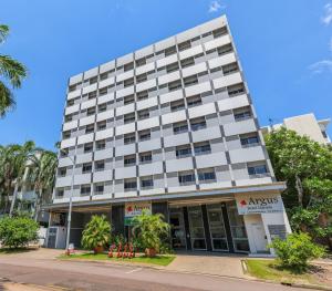 an apartment building on a street with palm trees at Argus Hotel Darwin in Darwin