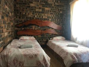 a bedroom with two beds and a brick wall at Monkey Mountain Family Lodge in Gemsbokfontein