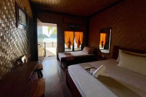 a bedroom with two beds and a window with orange curtains at Chislyk Inn in El Nido