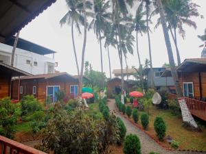 a resort with palm trees and a path with umbrellas at Mariners Bay Beach Resort in Arambol