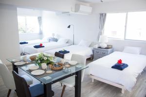 Zimmer mit 2 Betten, einem Tisch und Stühlen in der Unterkunft パークサイドモリ in Motobu