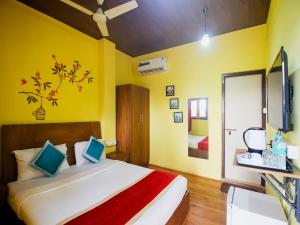 a bedroom with a bed and a yellow wall at Mariners Bay Beach Resort in Arambol