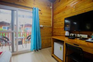 a room with a television and a balcony with a table at Mariners Bay Beach Resort in Arambol