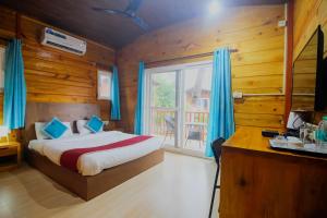 a bedroom with a bed with blue curtains and a window at Mariners Bay Beach Resort in Arambol