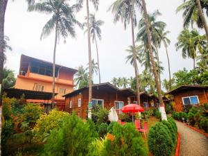 a resort with palm trees in front of a building at Mariners Bay Beach Resort in Arambol