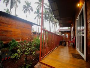 a porch of a house with palm trees in the background at Mariners Bay Beach Resort in Arambol