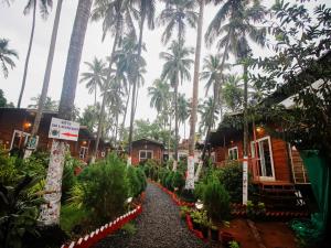 a path through a garden with palm trees in the background at Mariners Bay Beach Resort in Arambol
