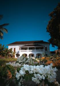 uma casa branca com flores à frente em The Manor House by Sansi em Zanzibar City