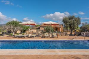 una piscina con sillas y sombrillas y una casa en Son Covas, en Santanyí