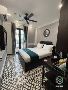 a bedroom with a bed with a ceiling fan and a television at Selecthotel Hạ Long in Ha Long