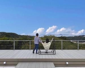 un homme assis sur une chaise sur une terrasse dans l'établissement Motobu Terrace, à Motobu