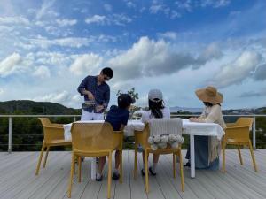 Un groupe de personnes assises autour d'une table sur une terrasse dans l'établissement Motobu Terrace, à Motobu