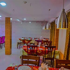 una sala da pranzo con tavoli e sedie in un ristorante di Eque Heritage Hotel & Resort a Lakshmanpur Bālāpāra