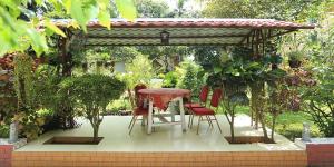 a table and chairs under a pergola in a garden at Eque Heritage Hotel & Resort in Lakshmanpur Bālāpāra