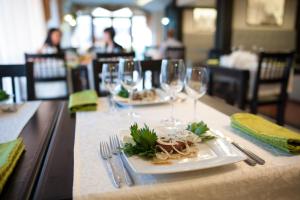 a table with two plates of food and wine glasses at Hotel Kopa - Lviv in Lviv