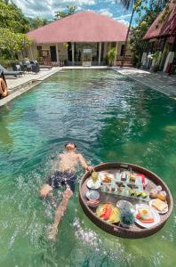 a man in a swimming pool with a tray of food at NDC Resort & Spa in Manado
