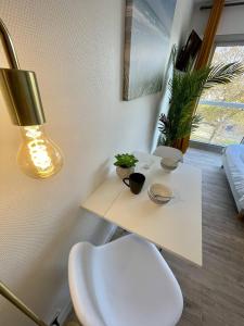 Cette chambre comprend une table blanche avec des plantes et une lampe. dans l'établissement Ma Location Sablaise - Appart' Le Chenal, à Les Sables-dʼOlonne