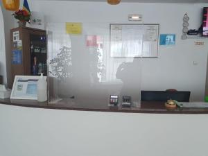 a counter in a office with a desk with a phone at Hotel Cornul Vanatorului in Piteşti
