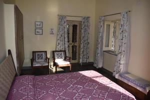 a bedroom with a purple bed and two chairs at Roda House - a boutique homestay in Bikaner in Bikaner